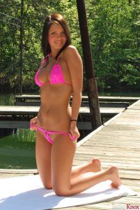 Girl slowly pulls down her pink bikini bottoms