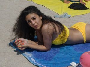 Girl in a yellow bikini poses on the beach