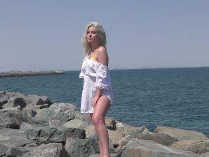 Blonde coed by the sea ready to pose for a daring photoshoot